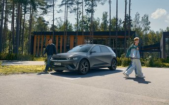 Grauer Hyundai IONIQ 5 vor einem modernen Gebäude in naturnaher Umgebung